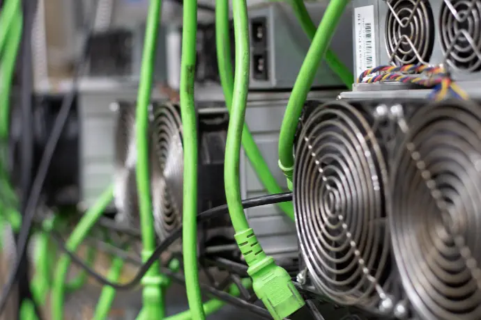 racked ASIC miners with green power cables waiting to be plugged in
