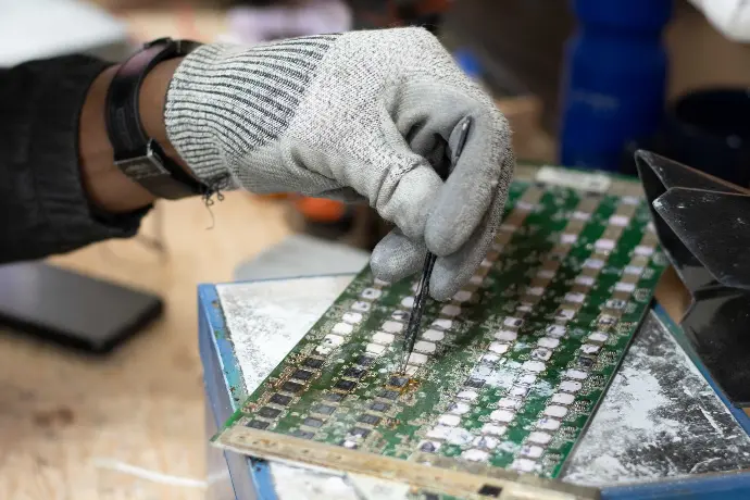 a technician's hand repairing chips on an ASIC hashboard 